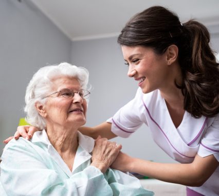 Smiling nurse and old woman patient at wheelchair at private nursing home